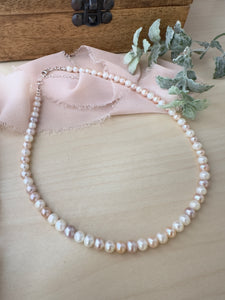 Alternating pink and white round freshwater Pearl necklace on a table 