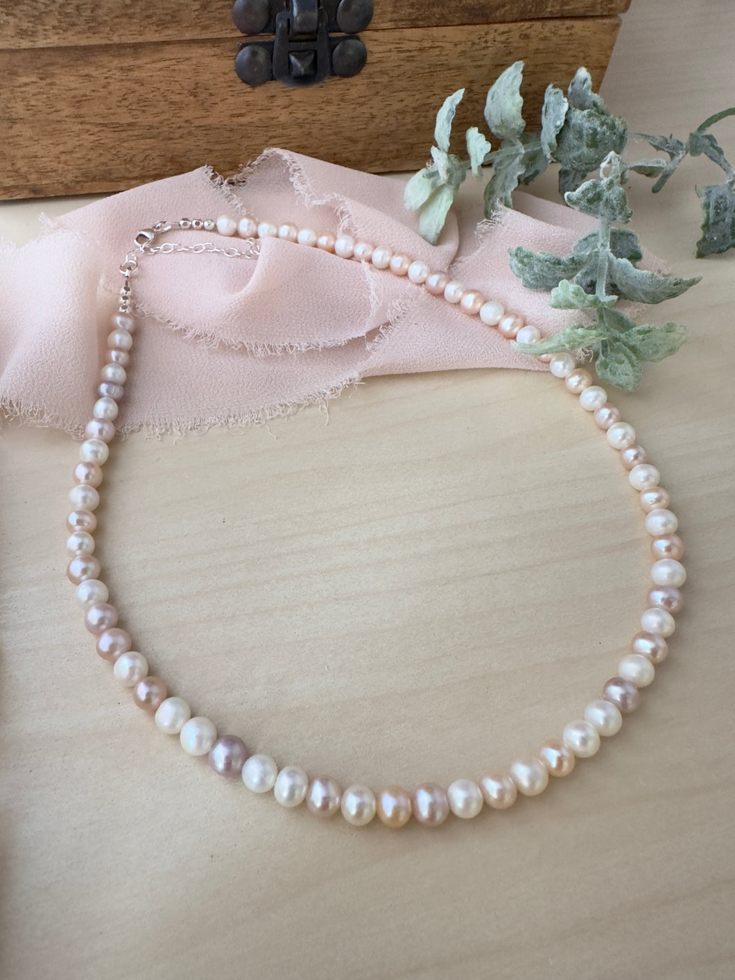 Alternating pink and white round freshwater Pearl necklace on a table 