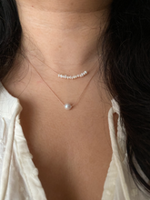 Load image into Gallery viewer, white freshwater pearl bar on a silk cord, shown worn along with a single pearl necklace. 