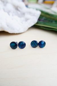 Two pairs of abalone earrings pictured sitting on a table 