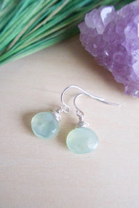 Sea fom green chalcedony gemstone drop earrings wire wrapped in sterling silver wire and suspended from sterling silver ear wires. Pictured on a table