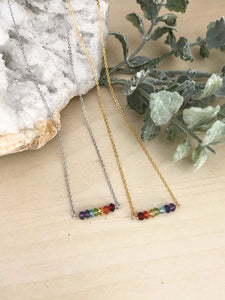 Rainbow bar necklaces laying on a table in a choice of silver or gold chain 